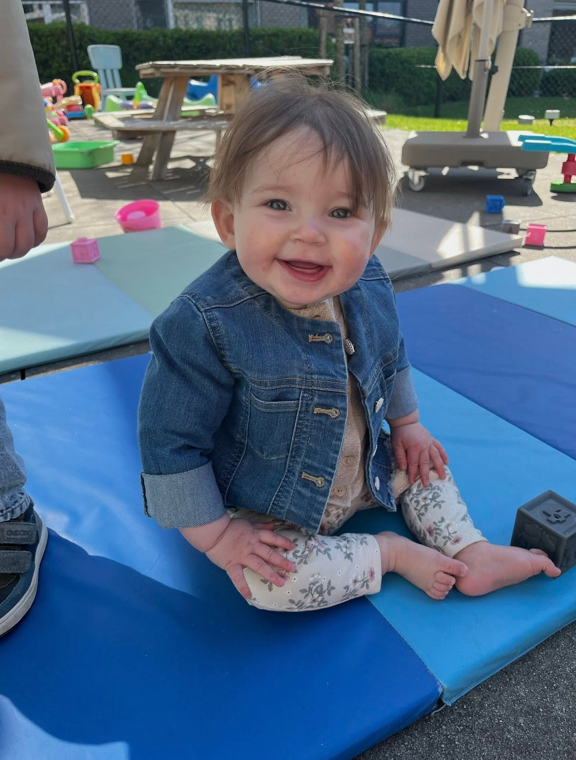 Vrolijke baby zit op een speelmat buiten