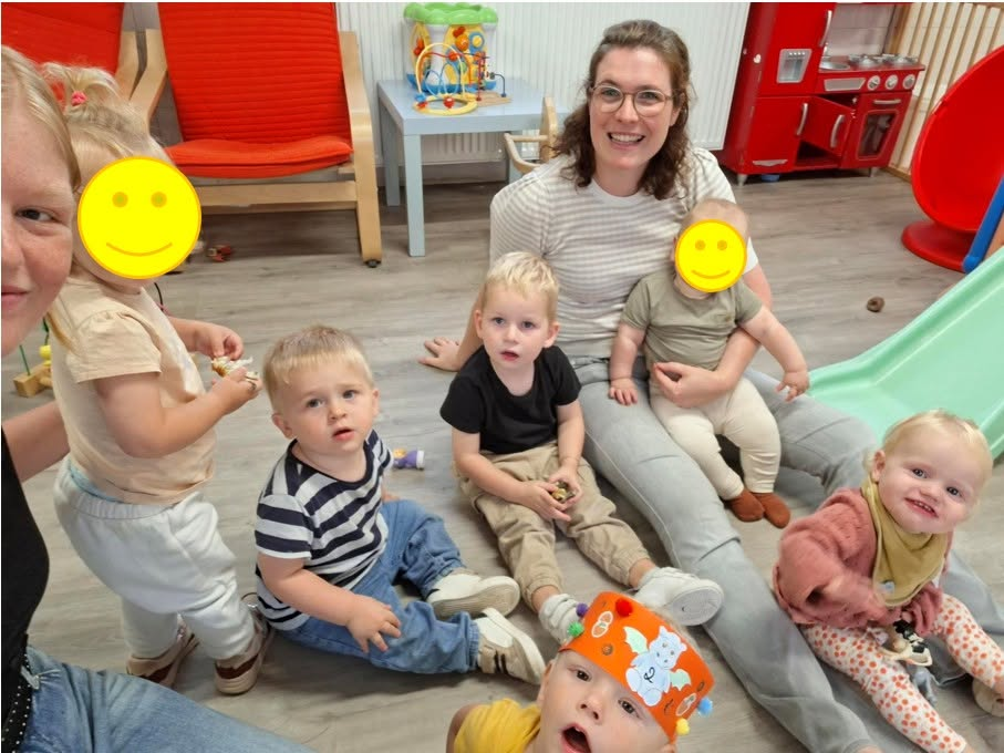 Begeleidster speelt binnen met een groepje baby's en peuters