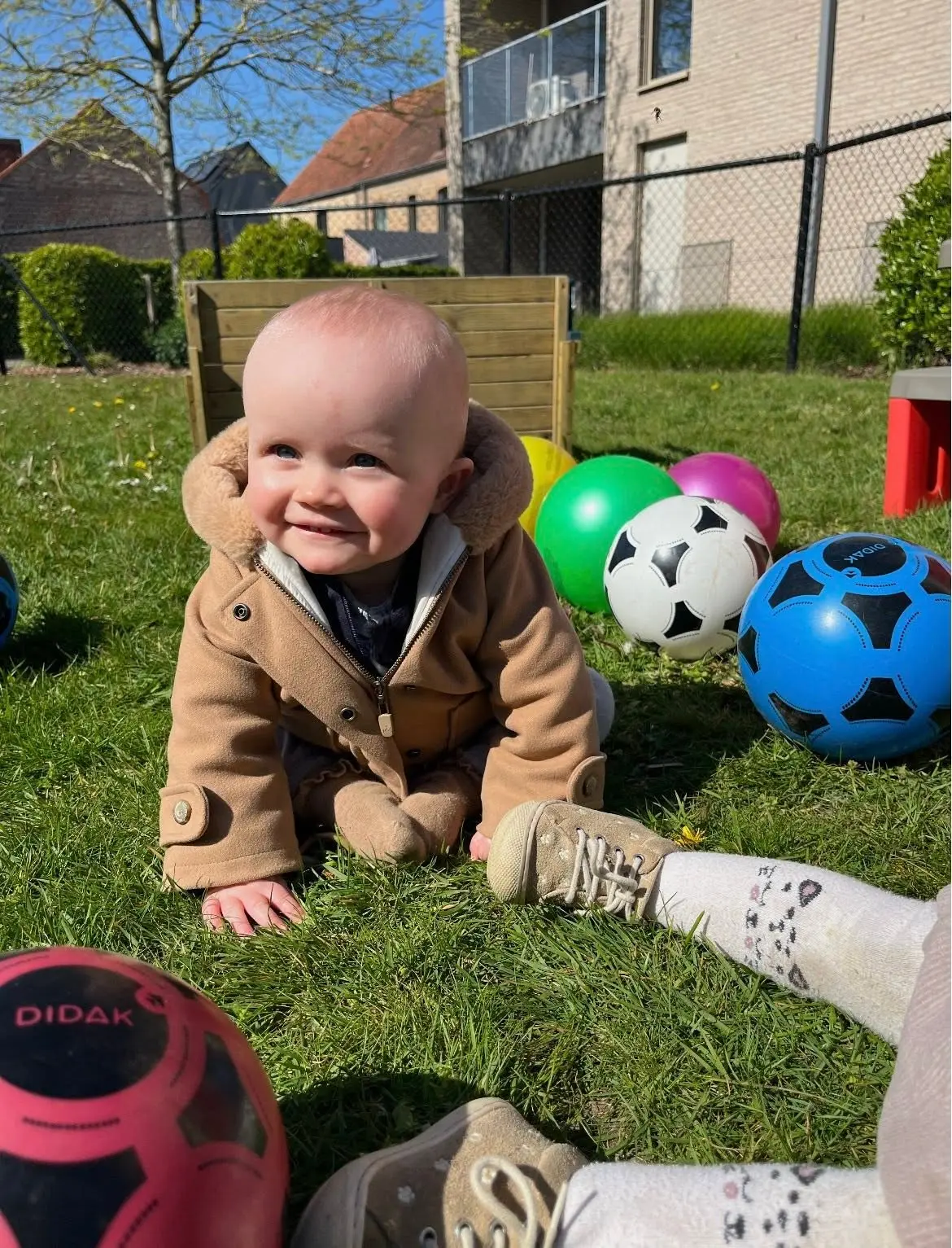 Lachende baby in het gras tussen speelballen